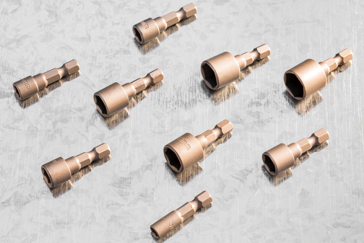 Zestaw komponentów technicznych ułożonych na blasze, ilustrujący profesjonalne elementy metalowe na zamówienie wykonane z wysokiej jakości stali